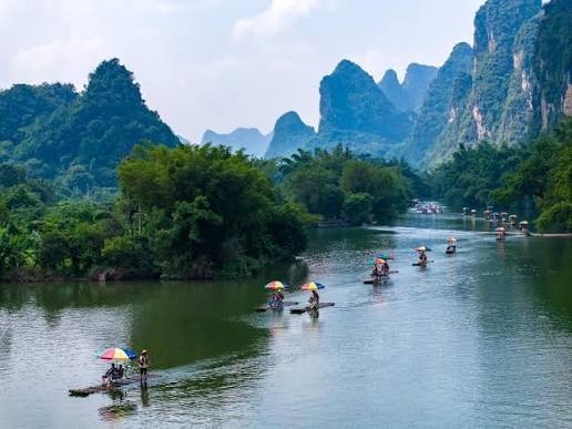Bamboo rafts floating along a quiet river surrounded by limestone mountains