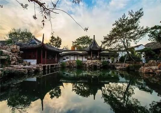 Classical Chinese garden with pavilions and trees reflected in a tranquil pond